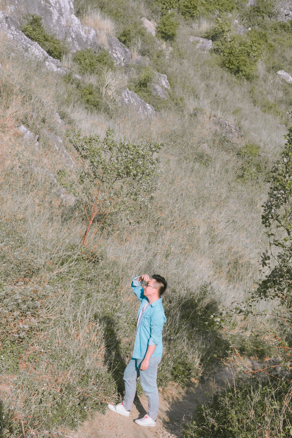 a young boy standing on a hill looking up at the sky