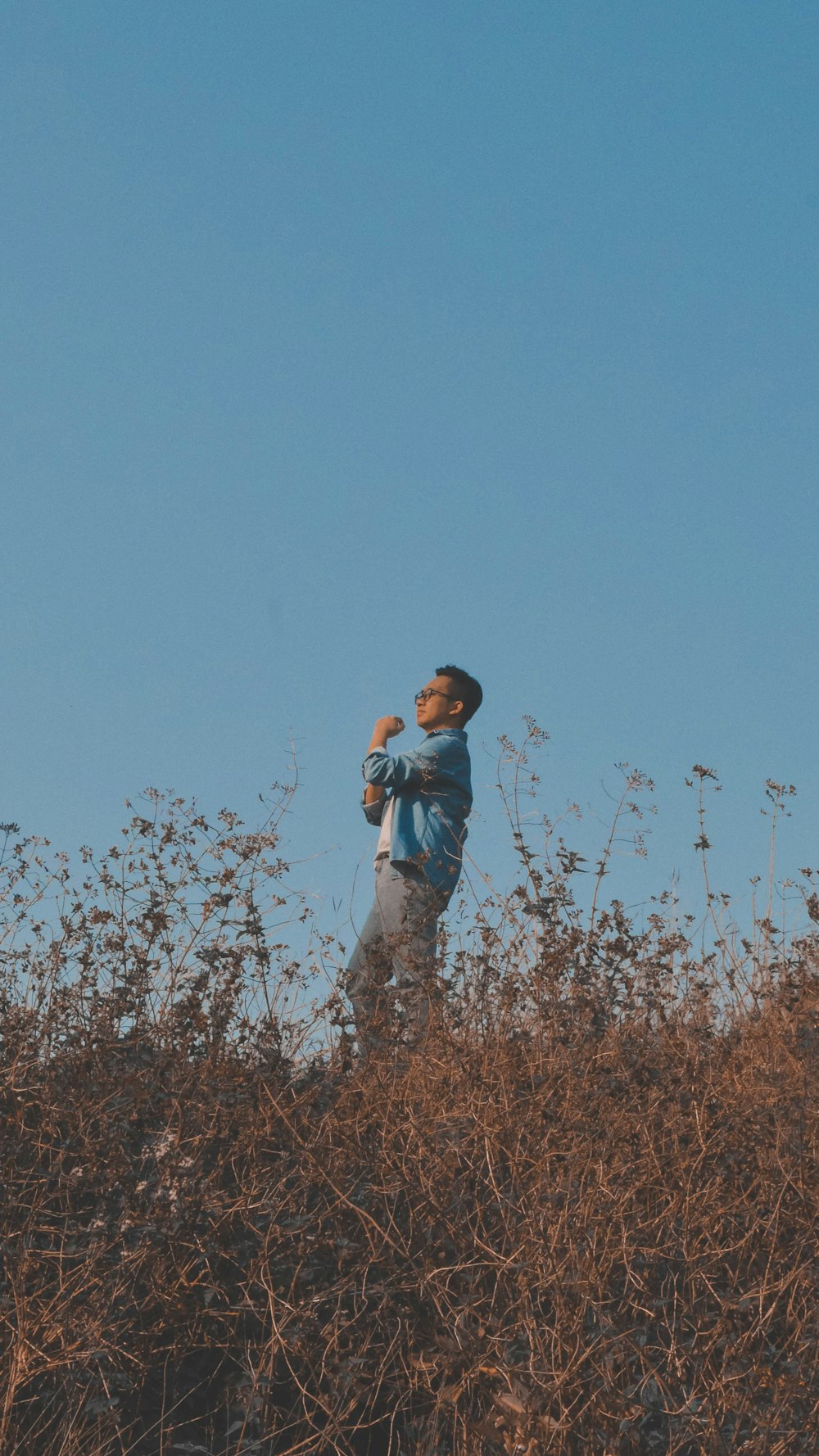 a man standing on top of a dry grass covered hillside