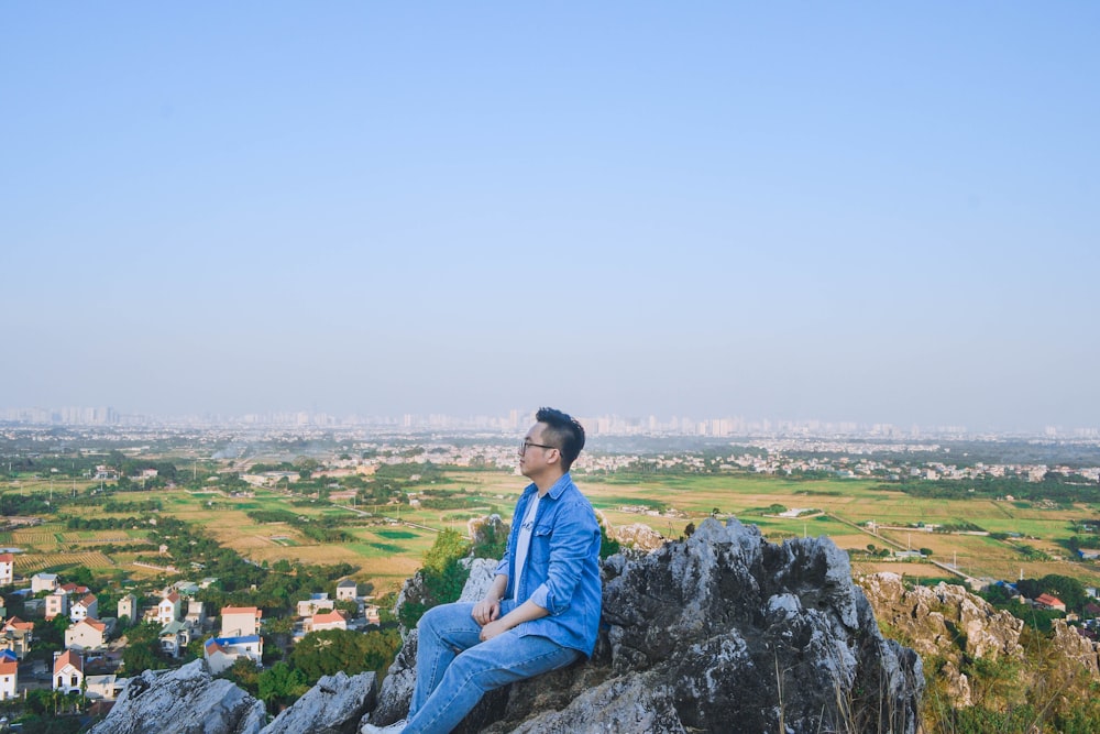 a man sitting on top of a large rock