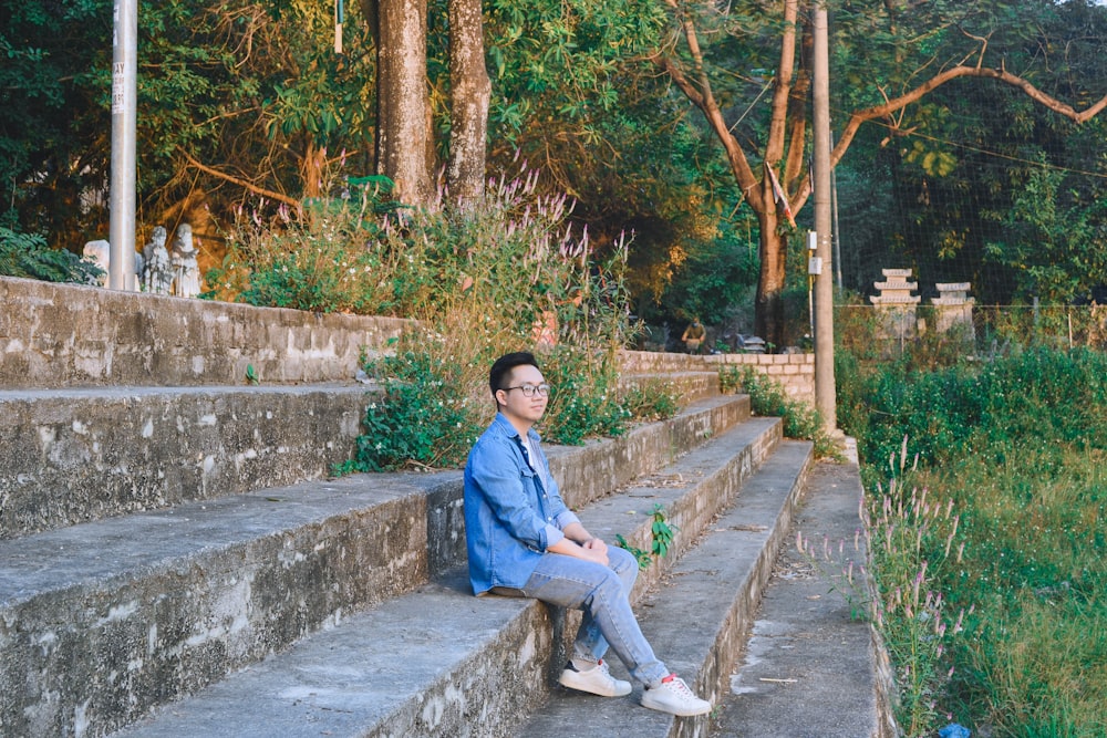 a man sitting on a stone step next to a forest