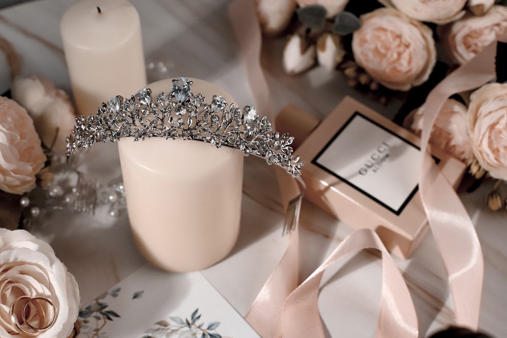Una tiara sentada en una mesa junto a una vela y flores