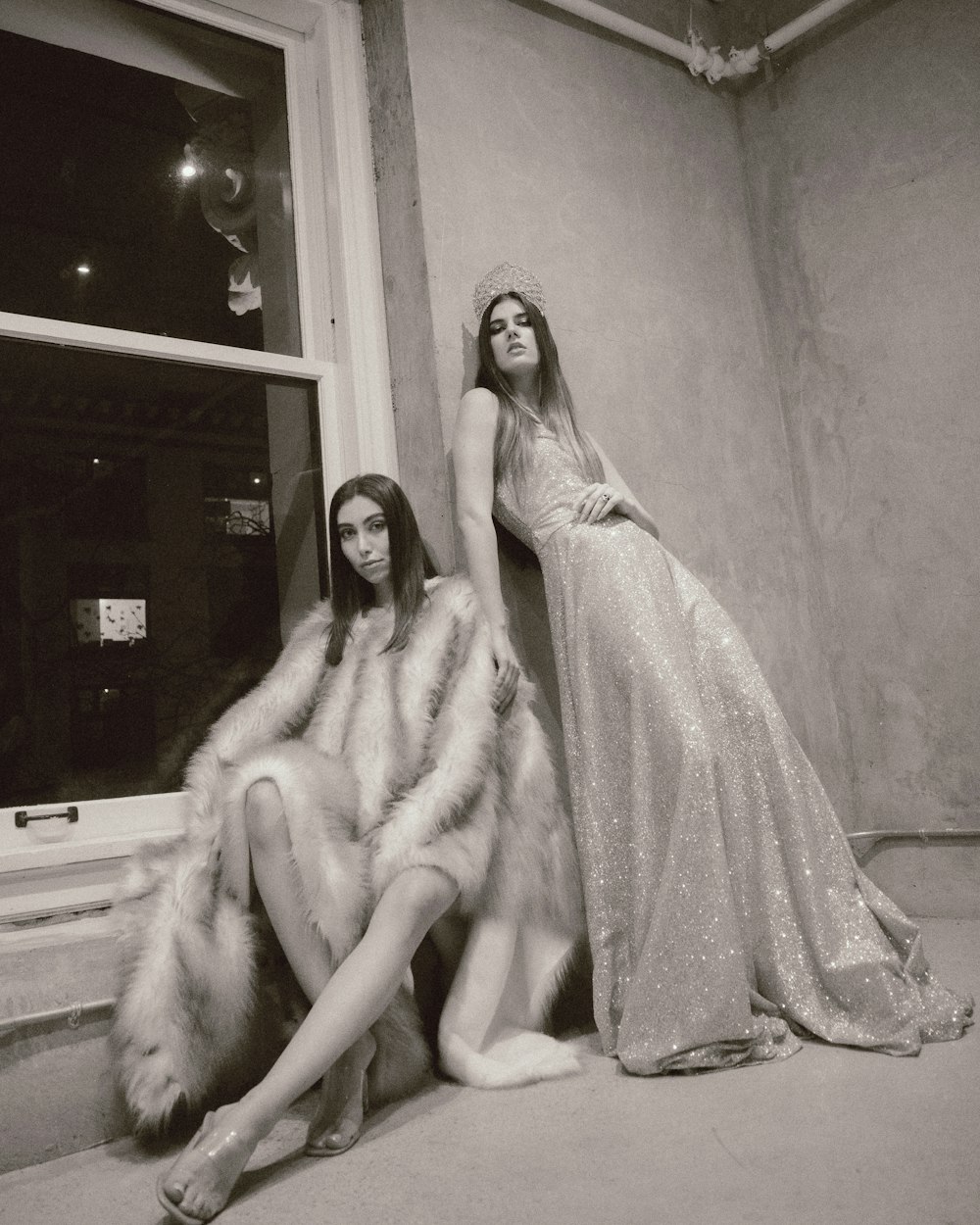 a couple of women sitting next to each other in front of a window