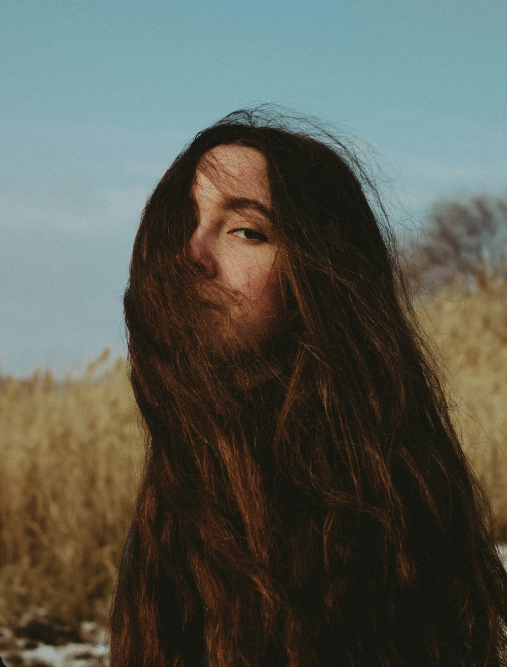 a man with long hair standing in a field