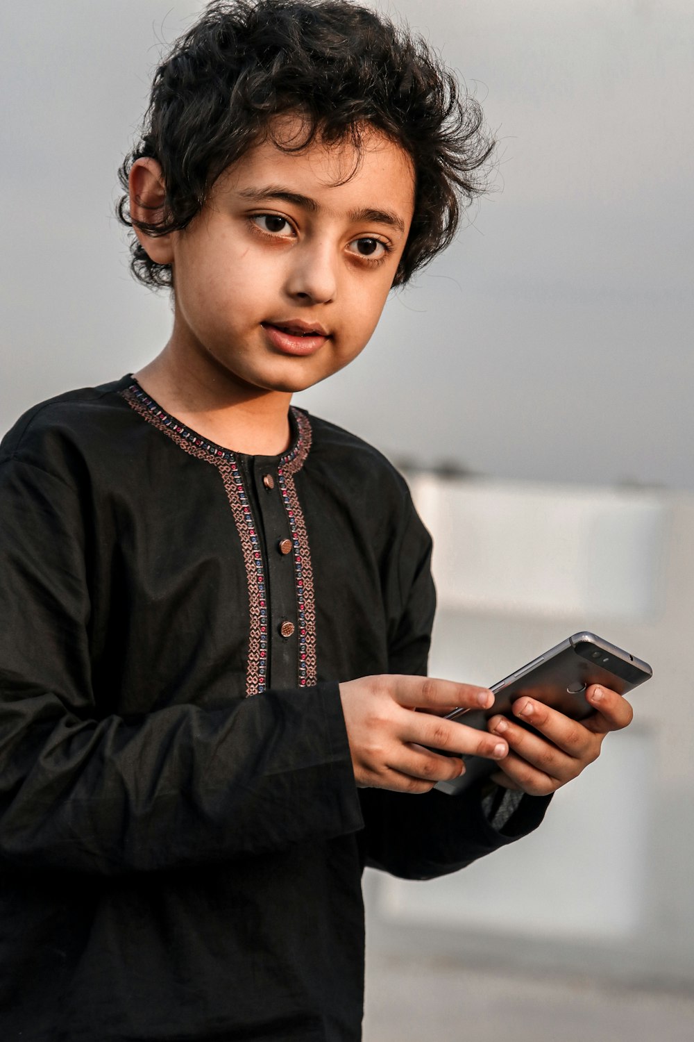 a young boy holding a smart phone in his hands
