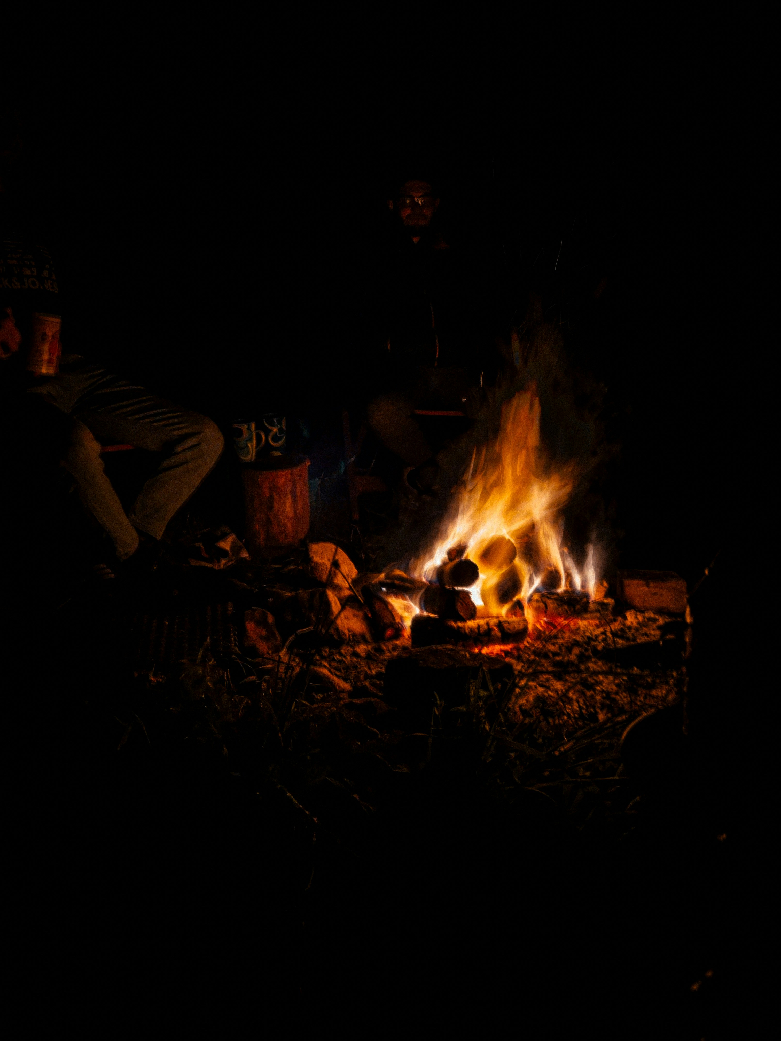 a person sitting in front of a fire in the dark