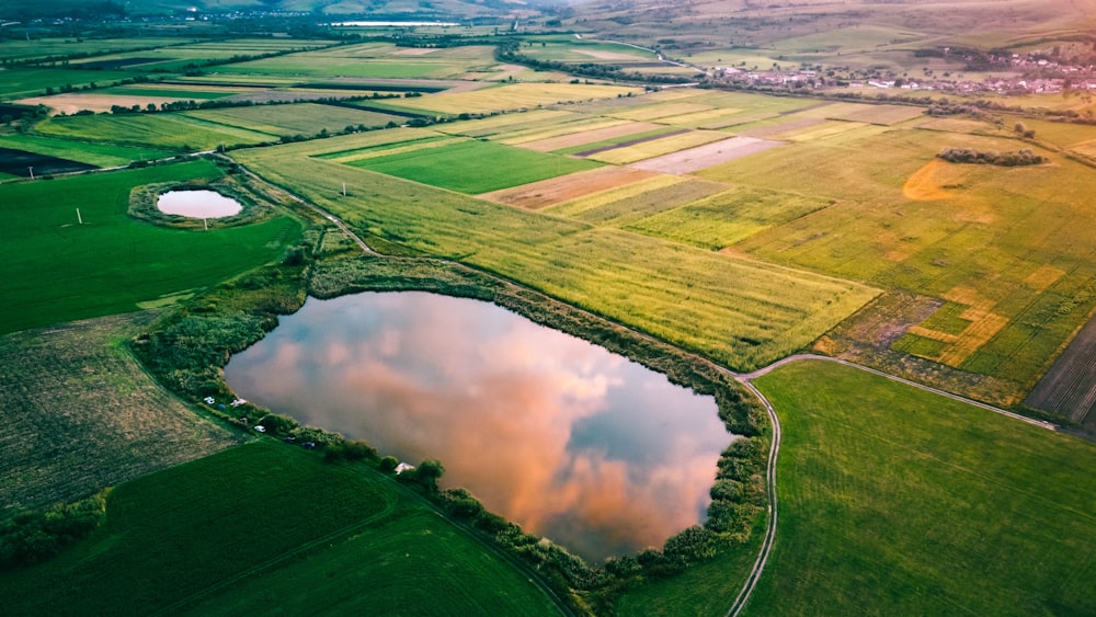 an aerial view of a lake surrounded by green fields