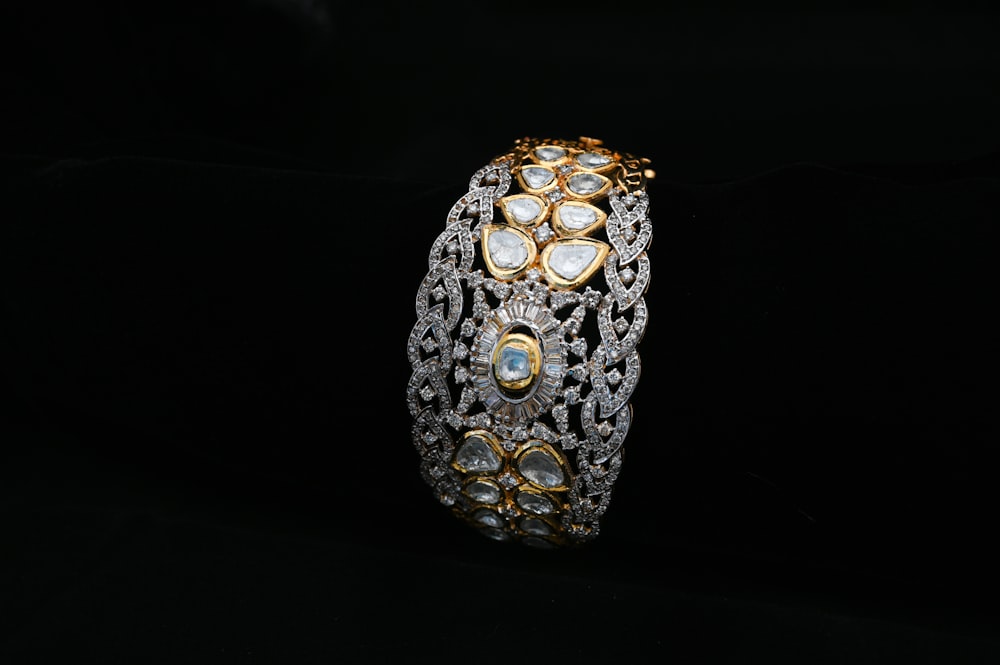 a gold and diamond bracelet on a black background