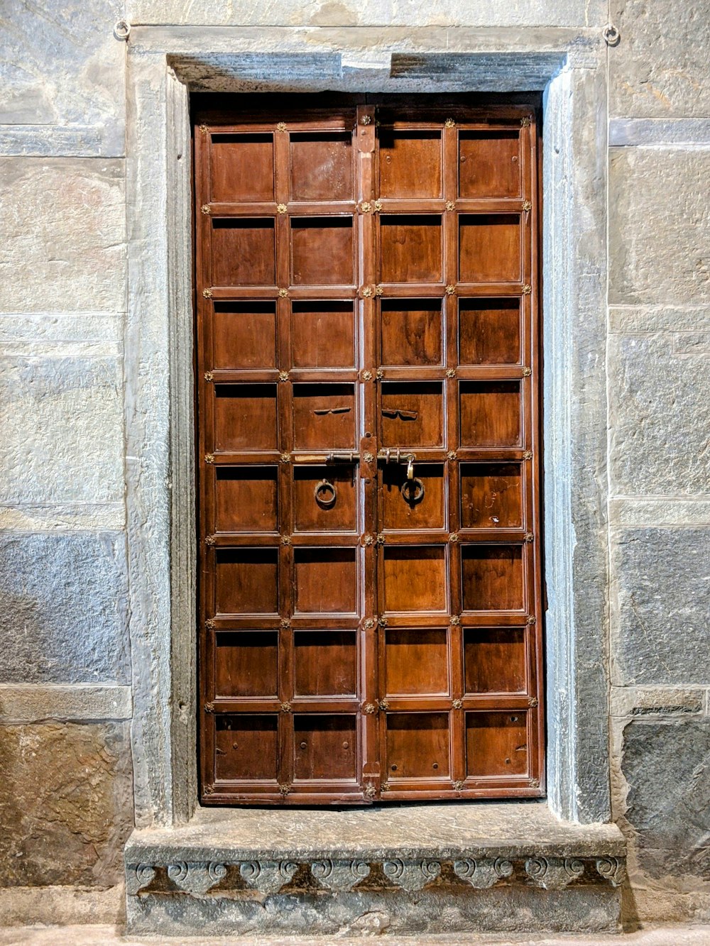 a wooden door with a lock on a stone building