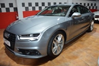 A silver luxury sedan gleaming under showroom lights with leather interiors visible.