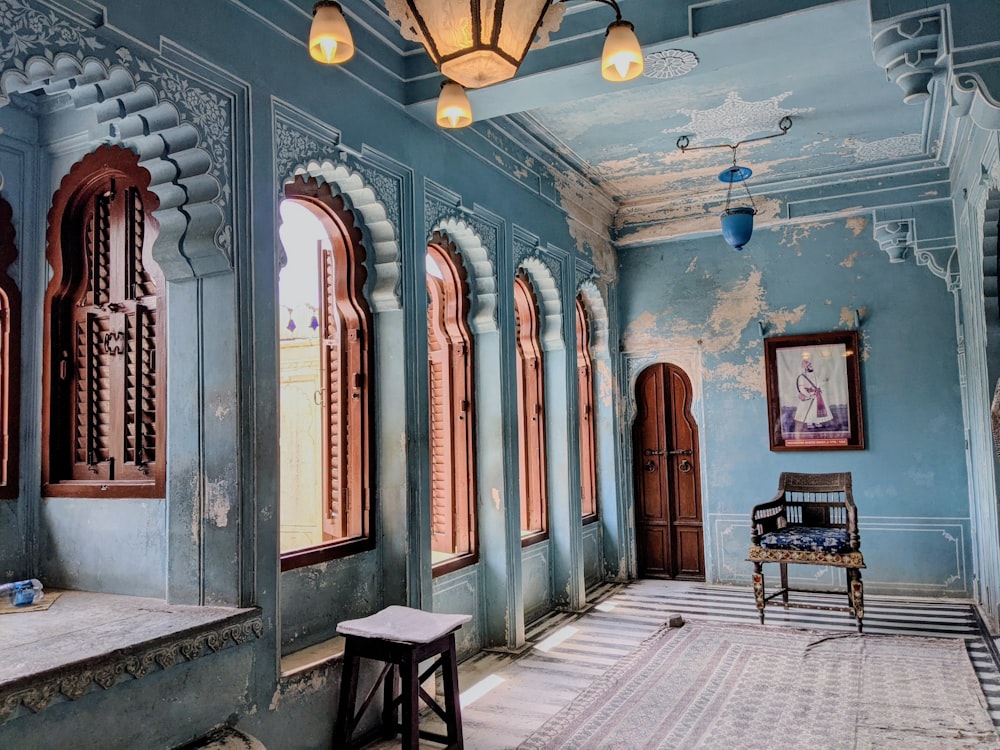 a blue room with a chair and windows