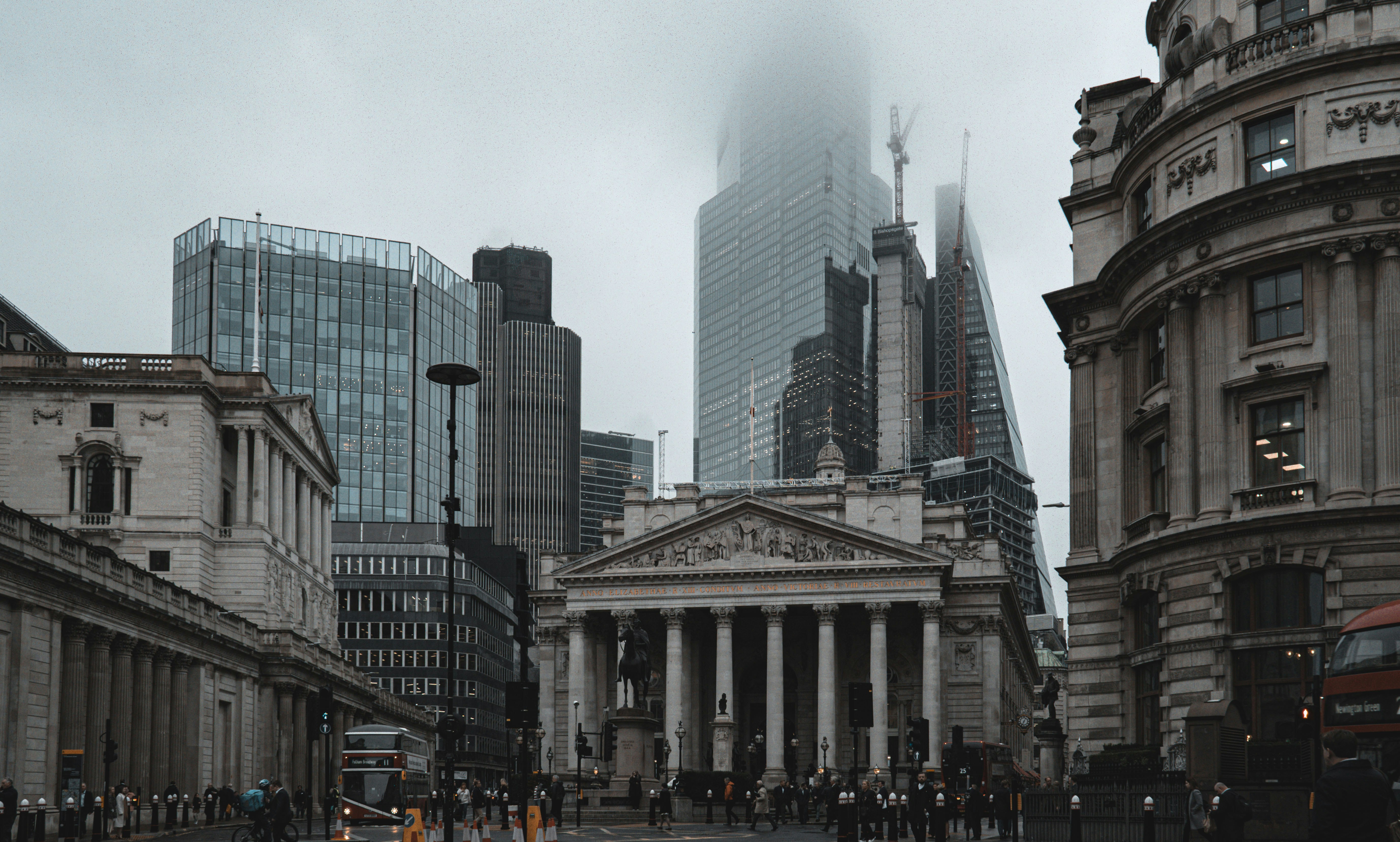 a group of people walking down a street next to tall buildings