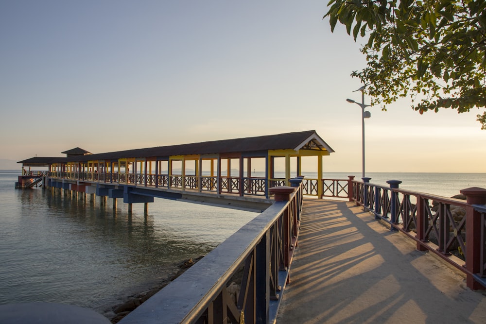 a long pier with benches on it next to the ocean