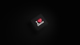 A dark background with a black square in the center. The square has the text 'I ❤️ DESIGN' with the heart symbol in red color.