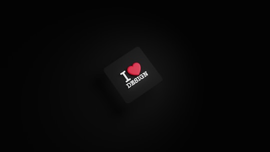 A dark background with a black square in the center. The square has the text 'I ❤️ DESIGN' with the heart symbol in red color.