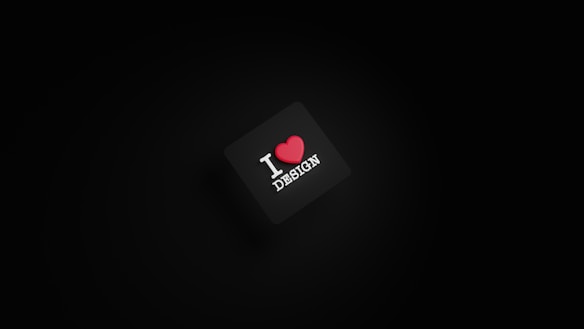 A dark background with a black square in the center. The square has the text 'I ❤️ DESIGN' with the heart symbol in red color.