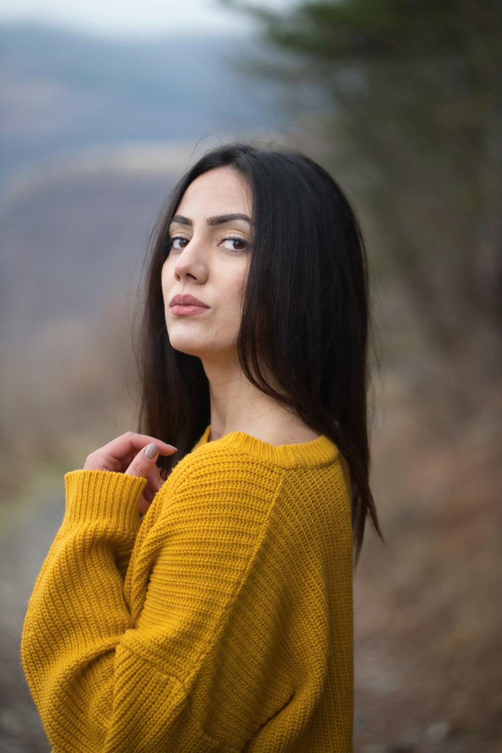 a woman in a yellow sweater poses for a picture