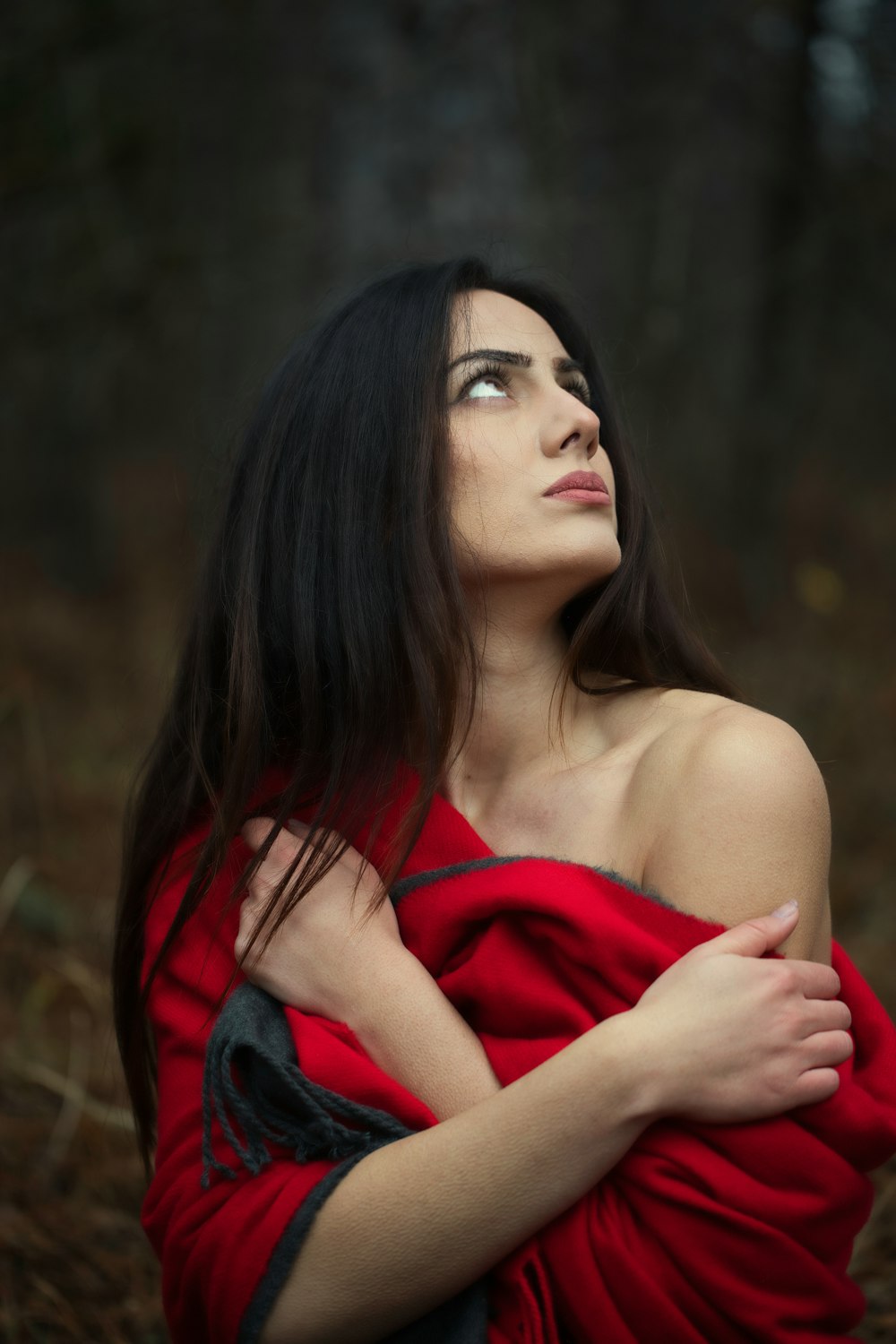 a woman in a red dress standing in the woods