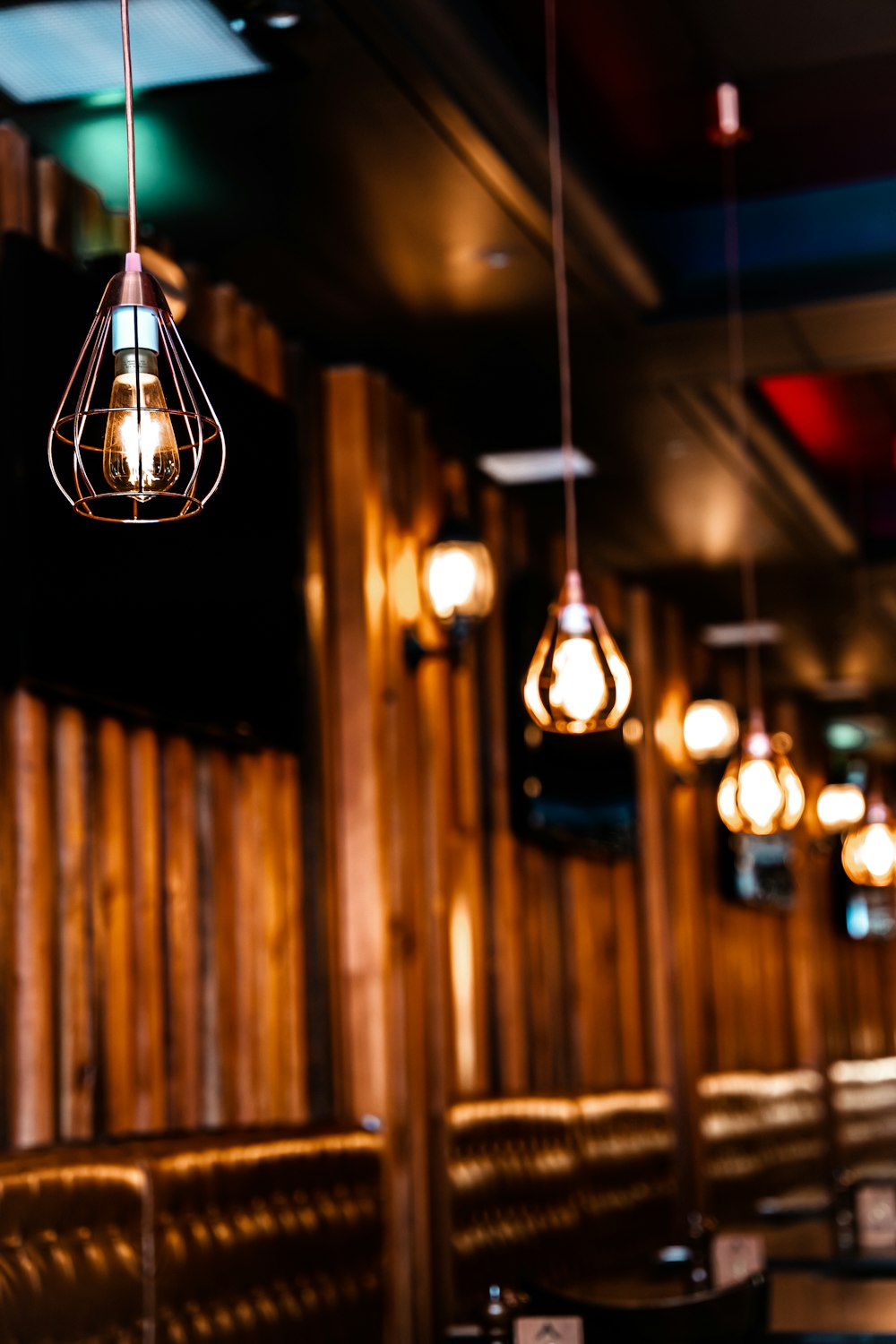 a restaurant with wooden booths and lights hanging from the ceiling