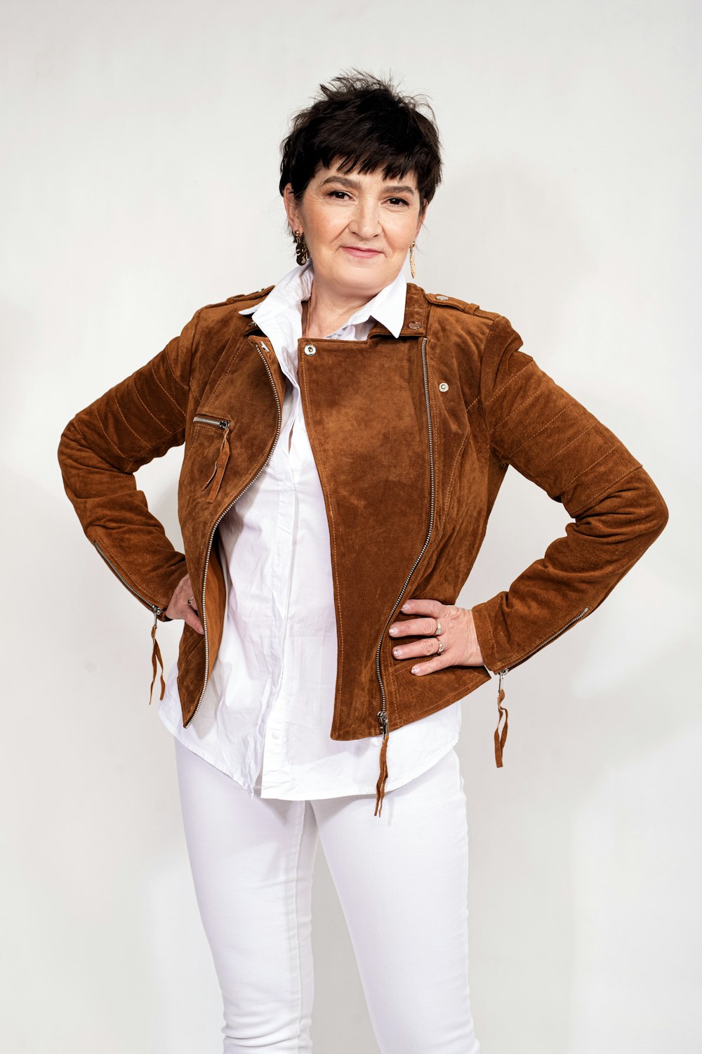 a woman in white pants and a brown jacket