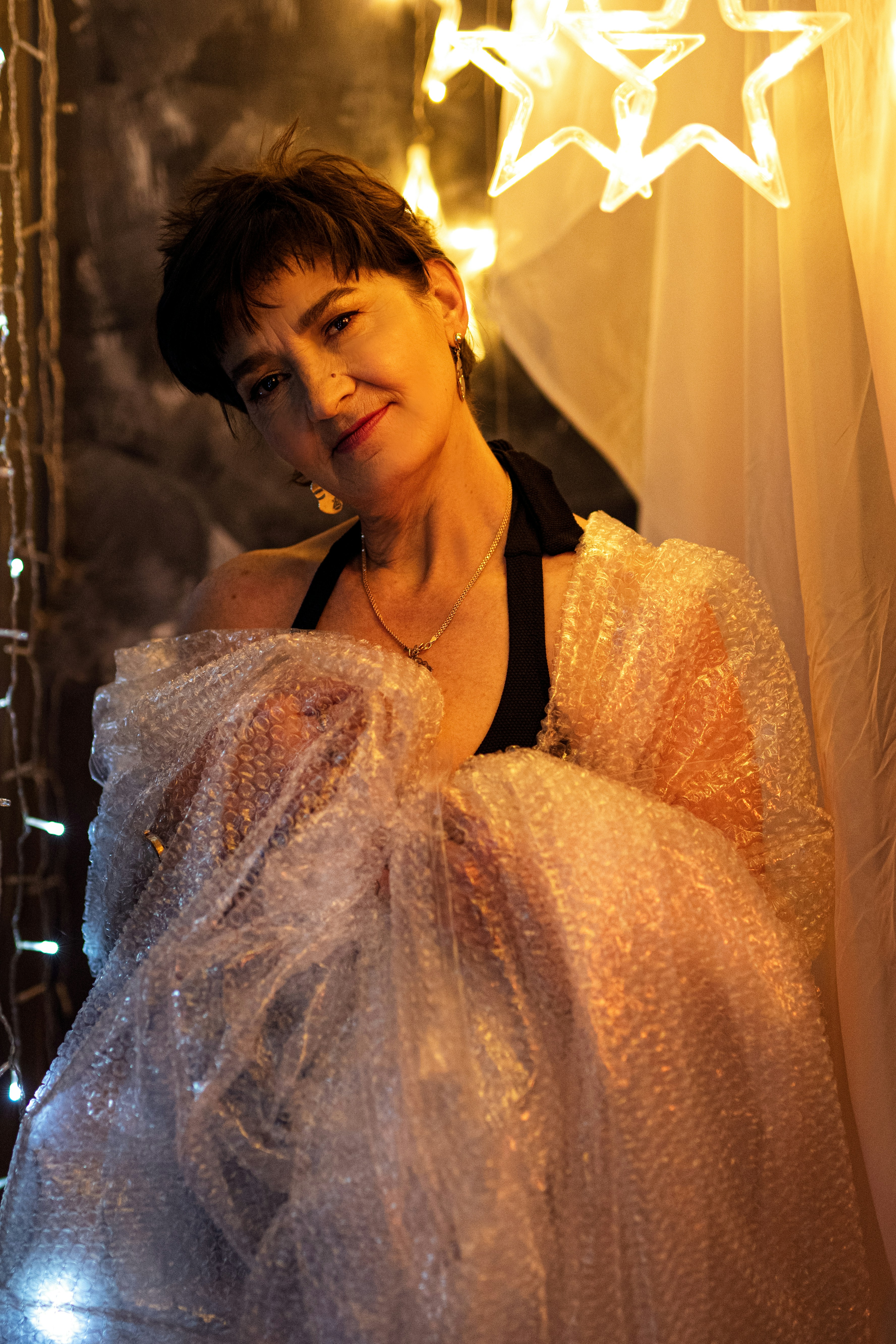 Eine Frau im weißen Kleid steht vor einem Vorhang