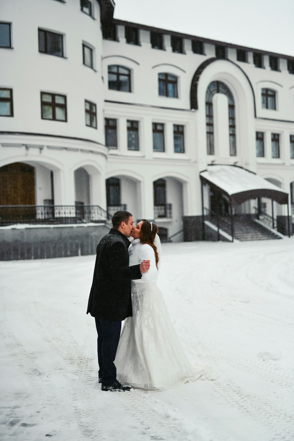 a man that is standing in the snow in front of a building