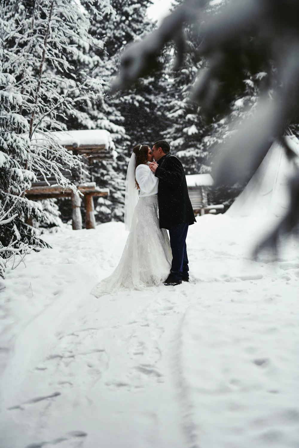 Bride and groom kissing in the snow at a winter wedding