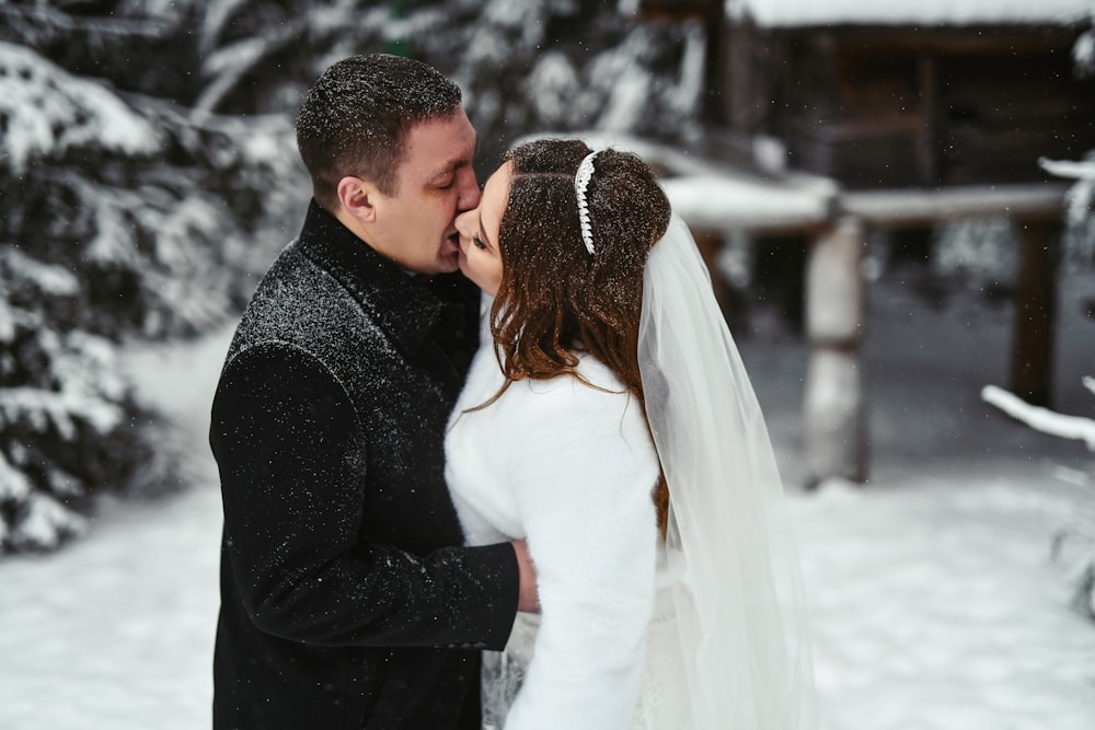 a bride and groom kissing in the snow