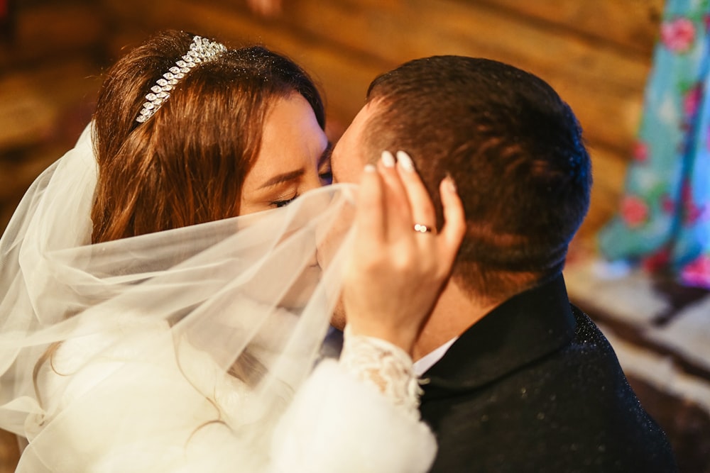 a bride and groom kissing under a veil