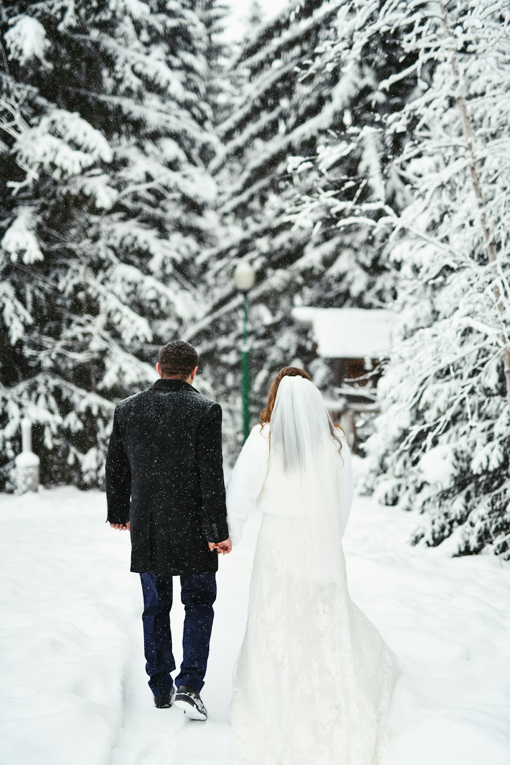 a bride and groom walking through the snow