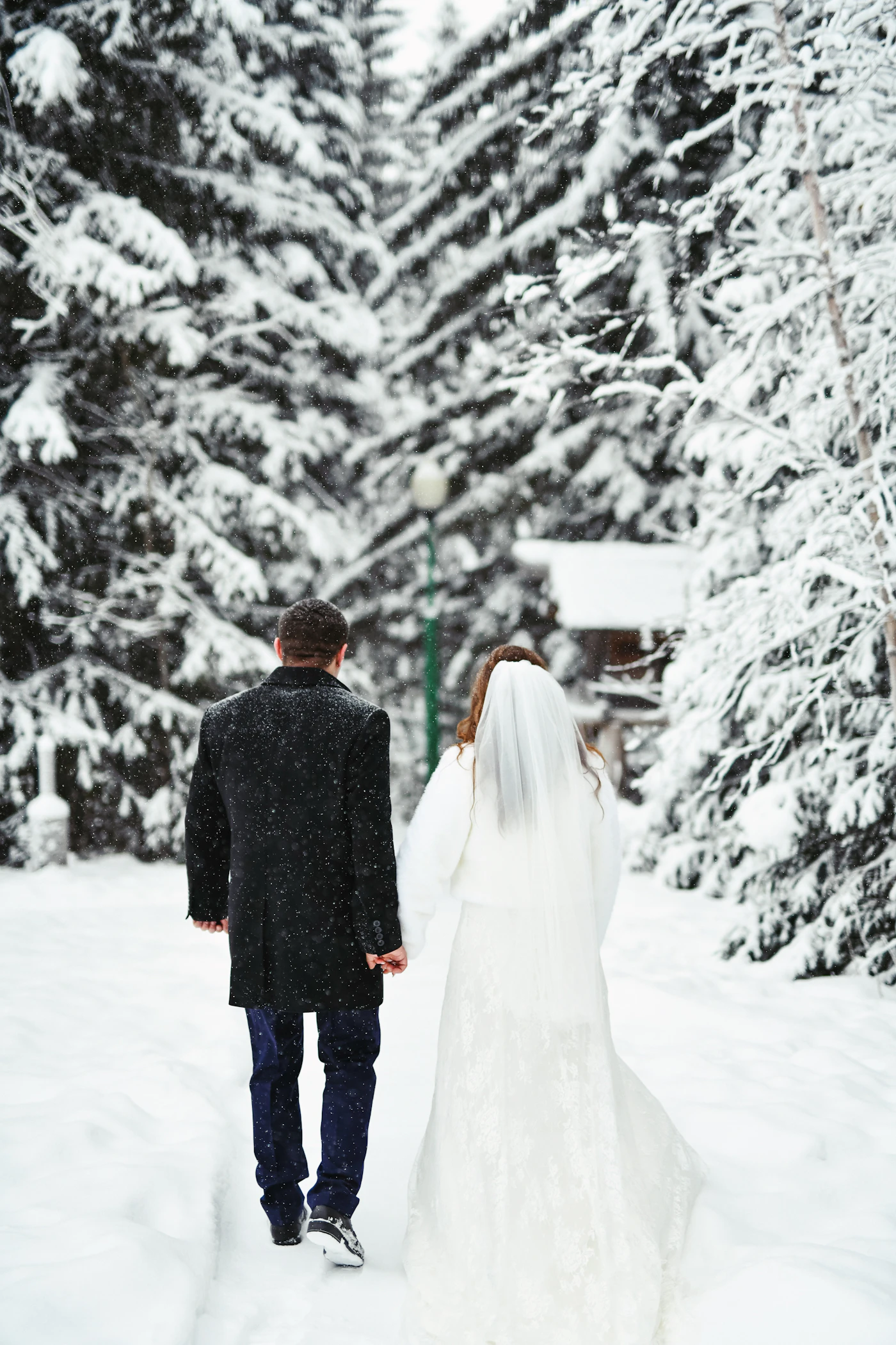 Winter wedding cape styles for cold climates — A bride wearing a flowing winter cape over her wedding gown.
