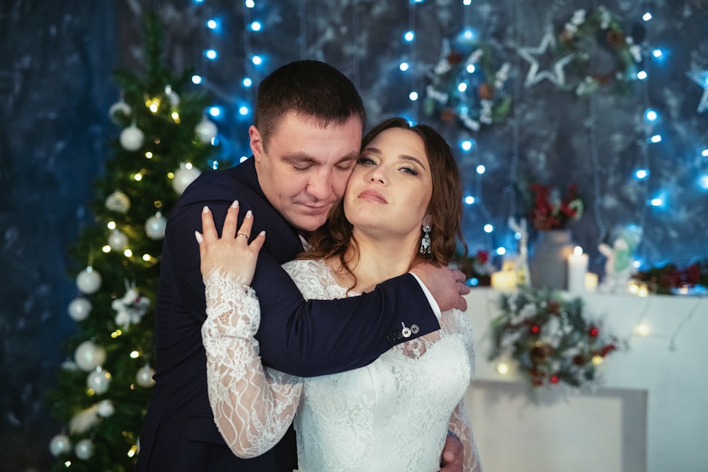 a man and a woman hugging in front of a christmas tree