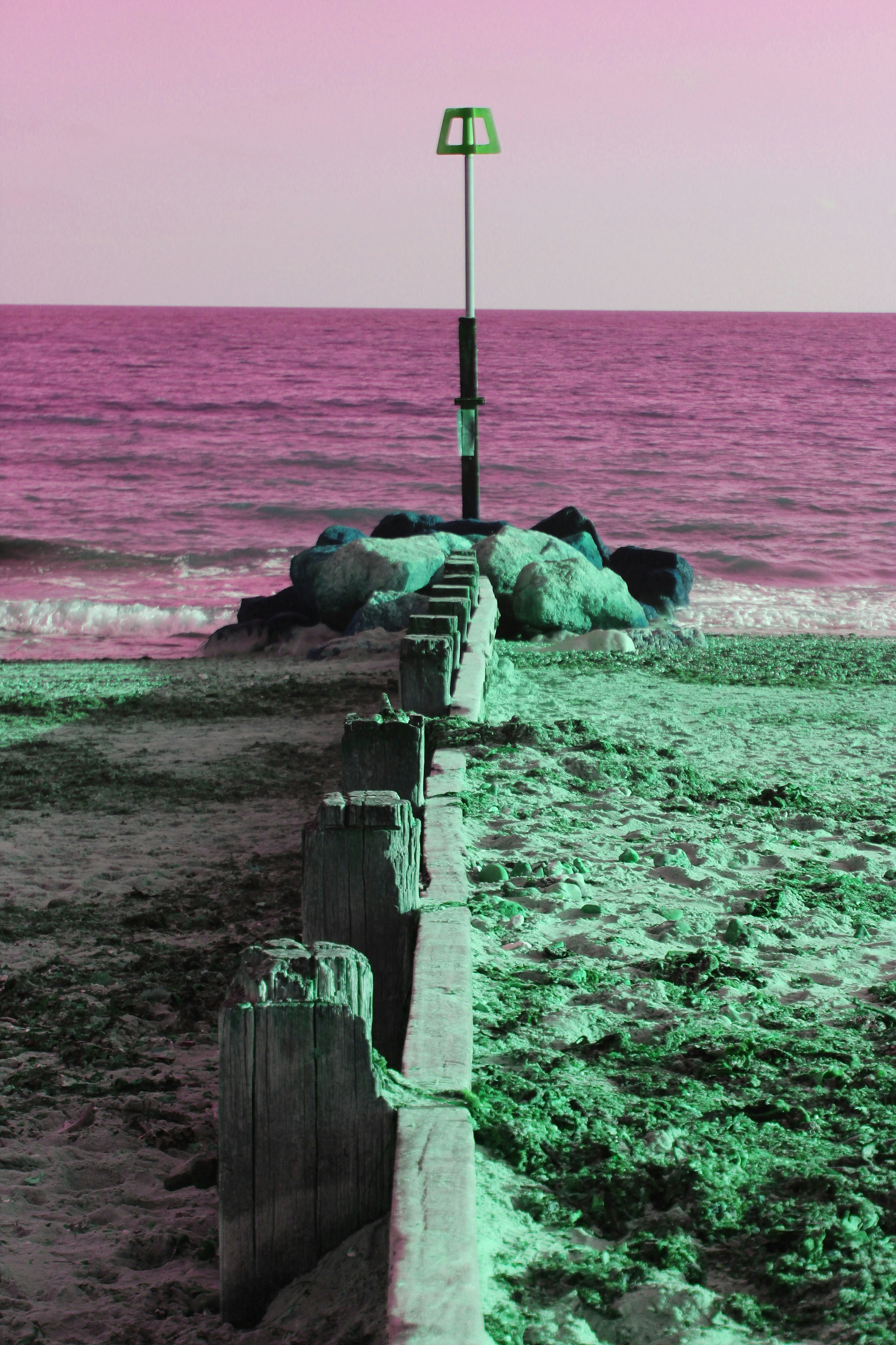 a wooden fence on a beach next to the ocean