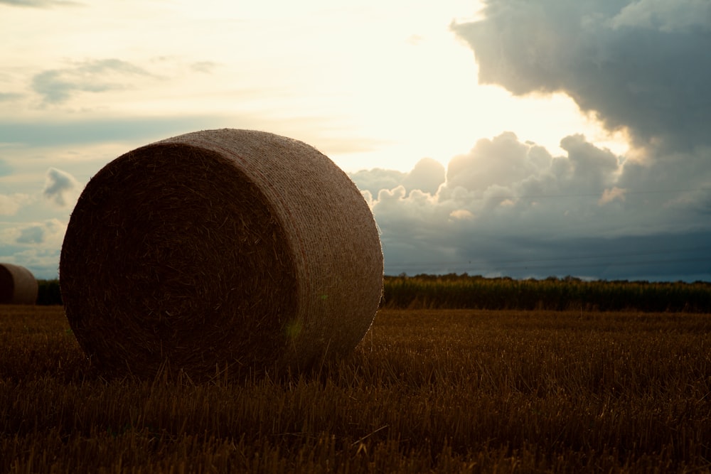 a hay bale in a field at sunset