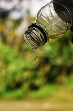 Close-up of a clear bottle pouring white PVA adhesive onto a wooden surface.
