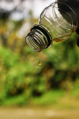 Close-up of a clear bottle pouring white PVA adhesive onto a wooden surface.