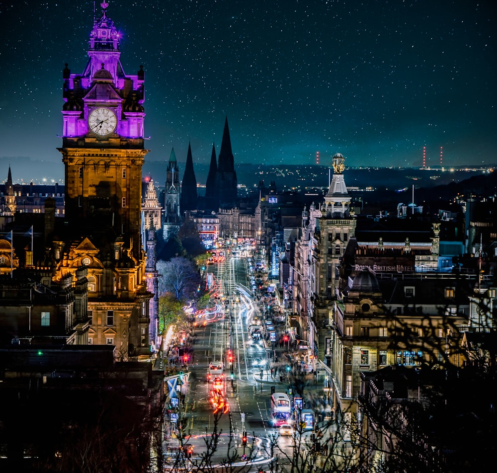 a city street at night with a clock tower in the background