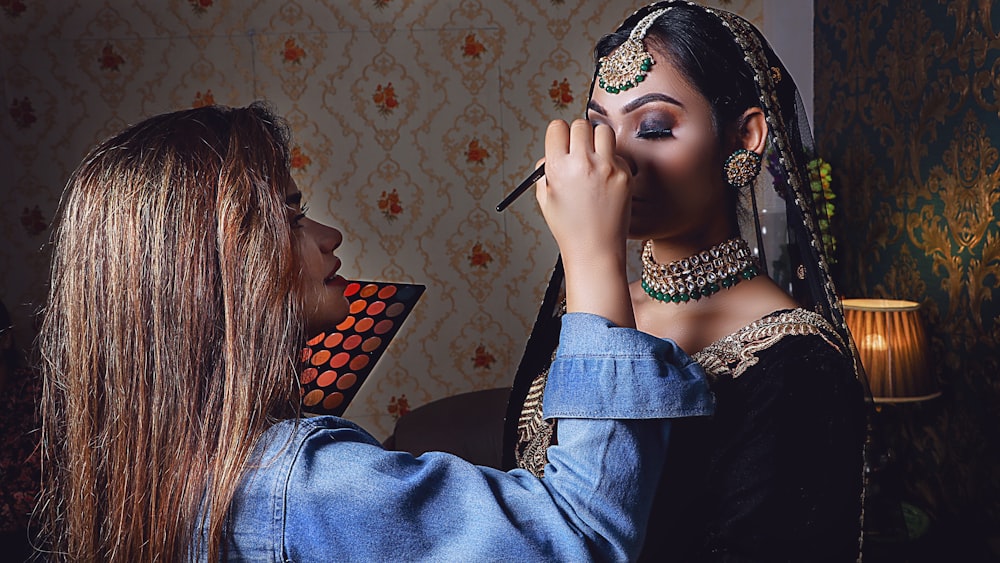 a woman putting makeup on another woman's face