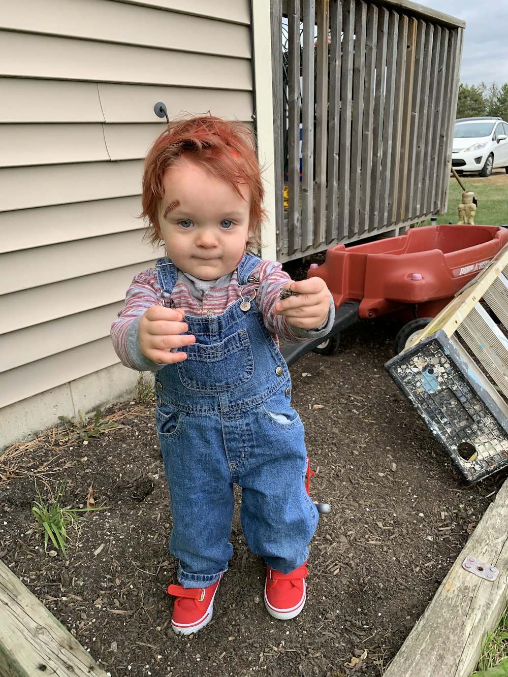 Une petite fille aux cheveux roux debout dans un jardin