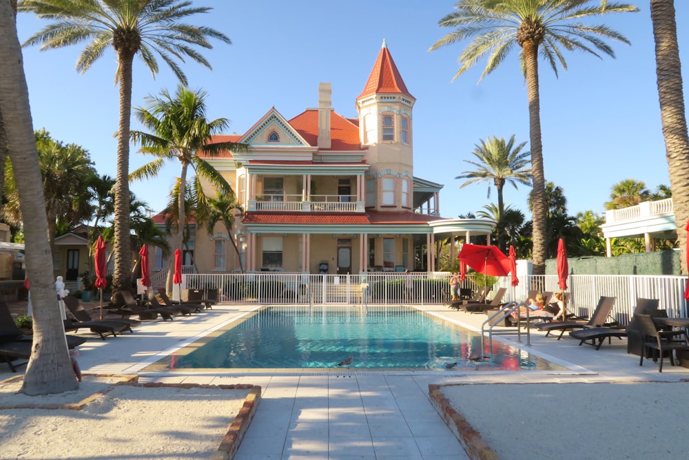 a large house with a swimming pool surrounded by palm trees