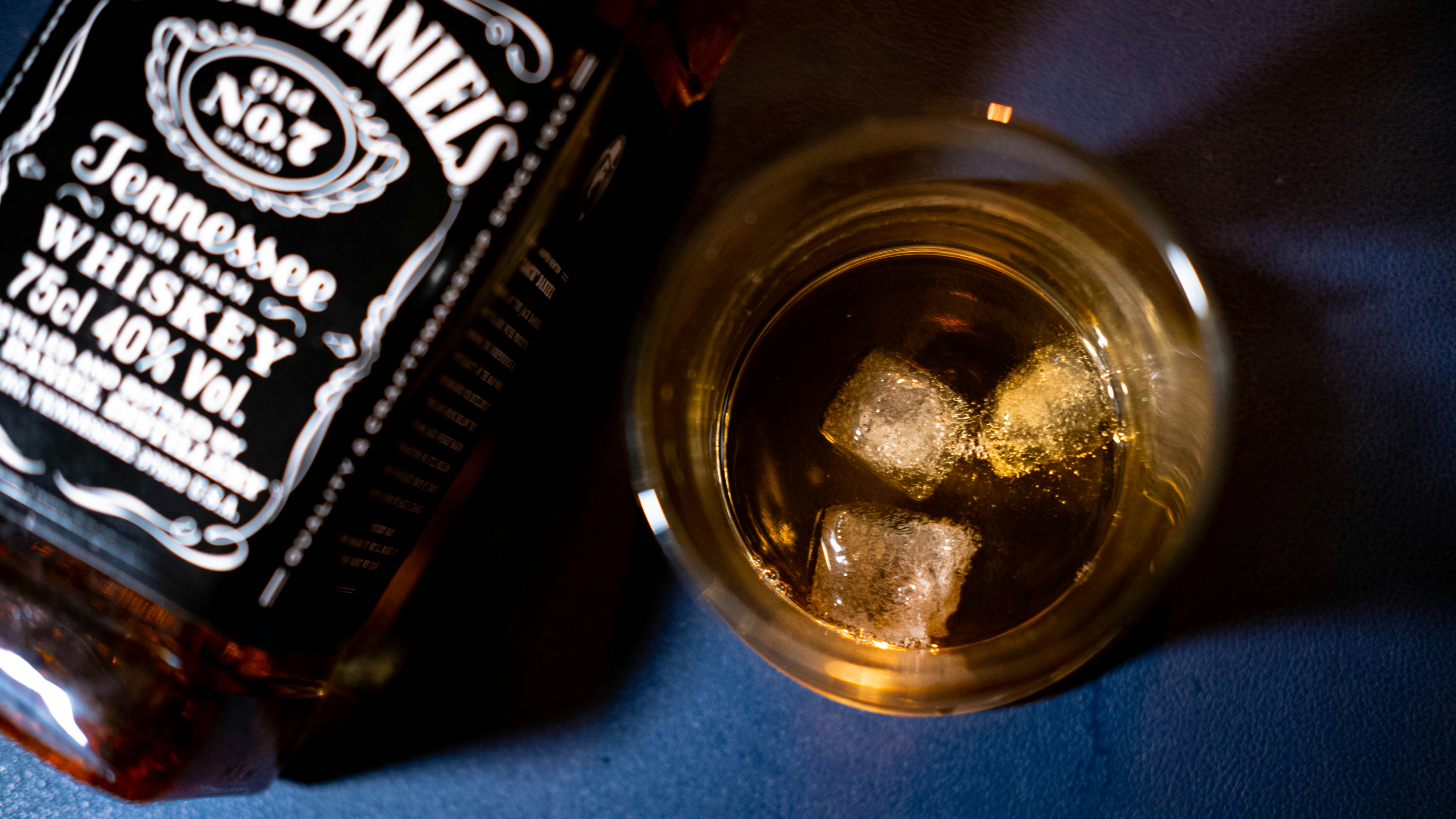 a bottle of whiskey next to a glass filled with ice cubes