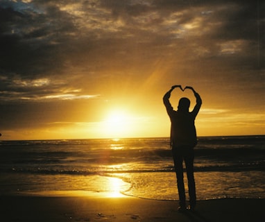 a person standing on a beach with their hands in the air