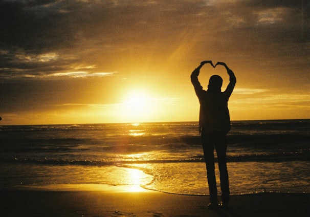 a person standing on a beach with their hands in the air