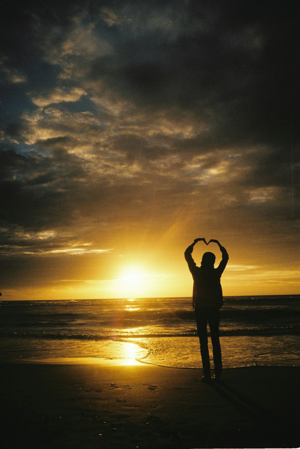 a person standing on a beach with their hands in the air