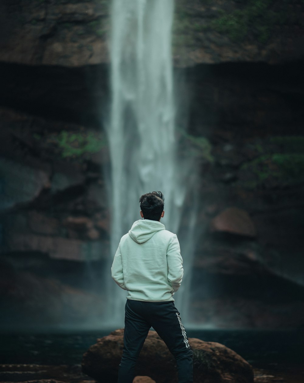 a man standing in front of a waterfall