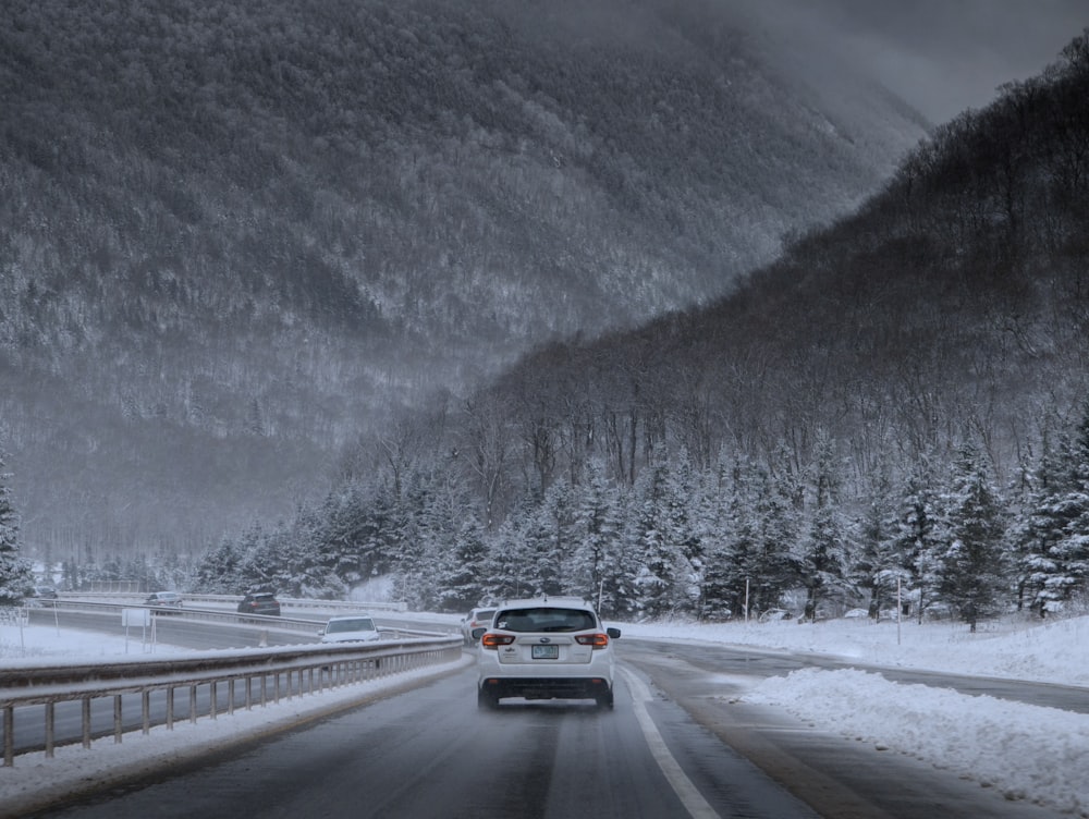 a car driving down a snowy road in the mountains