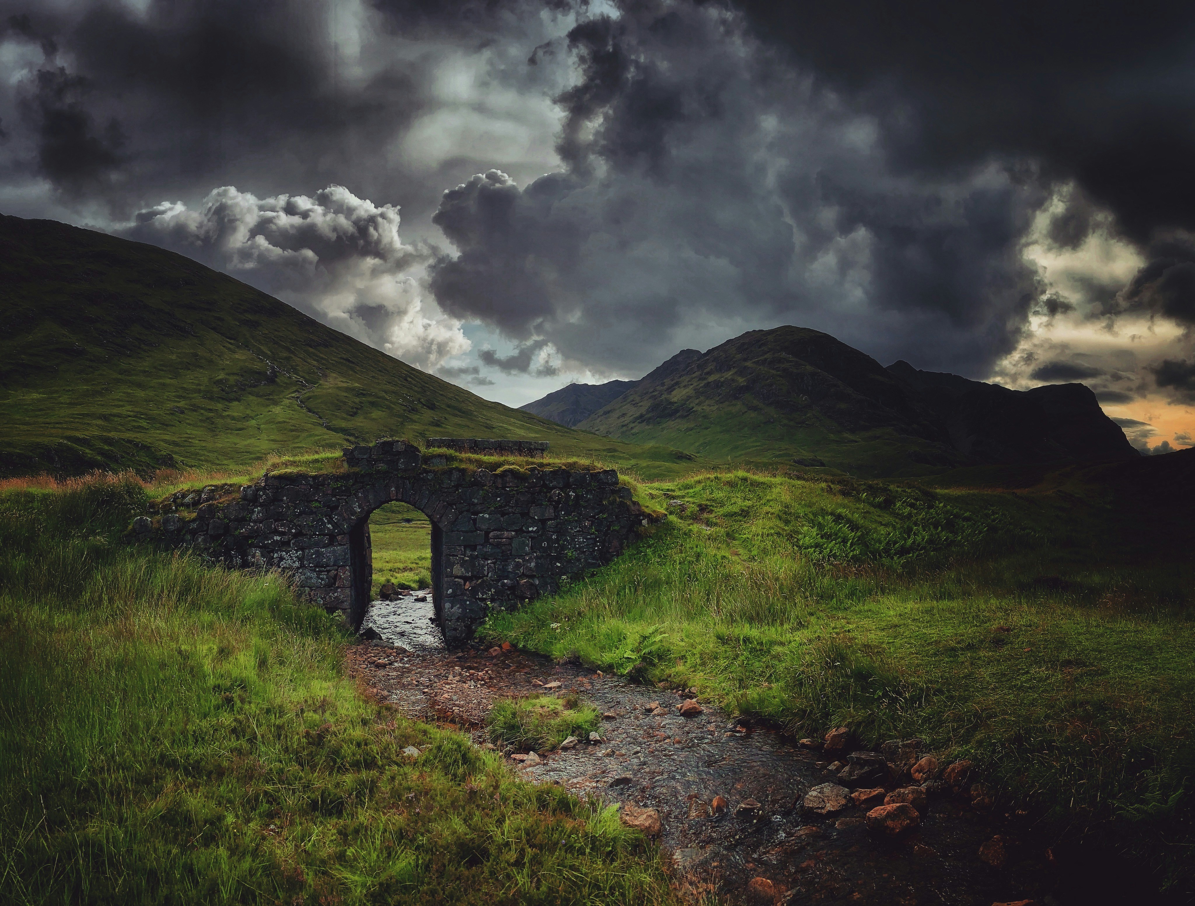 uma ponte de pedra no meio de um campo gramado