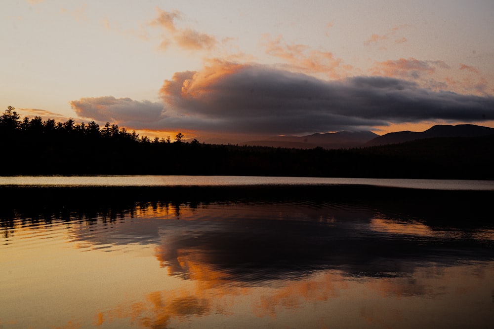 Le soleil se couche sur un lac avec des montagnes en arrière-plan