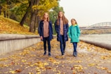 Parents and children hiking up a rocky path with colorful autumn leaves.