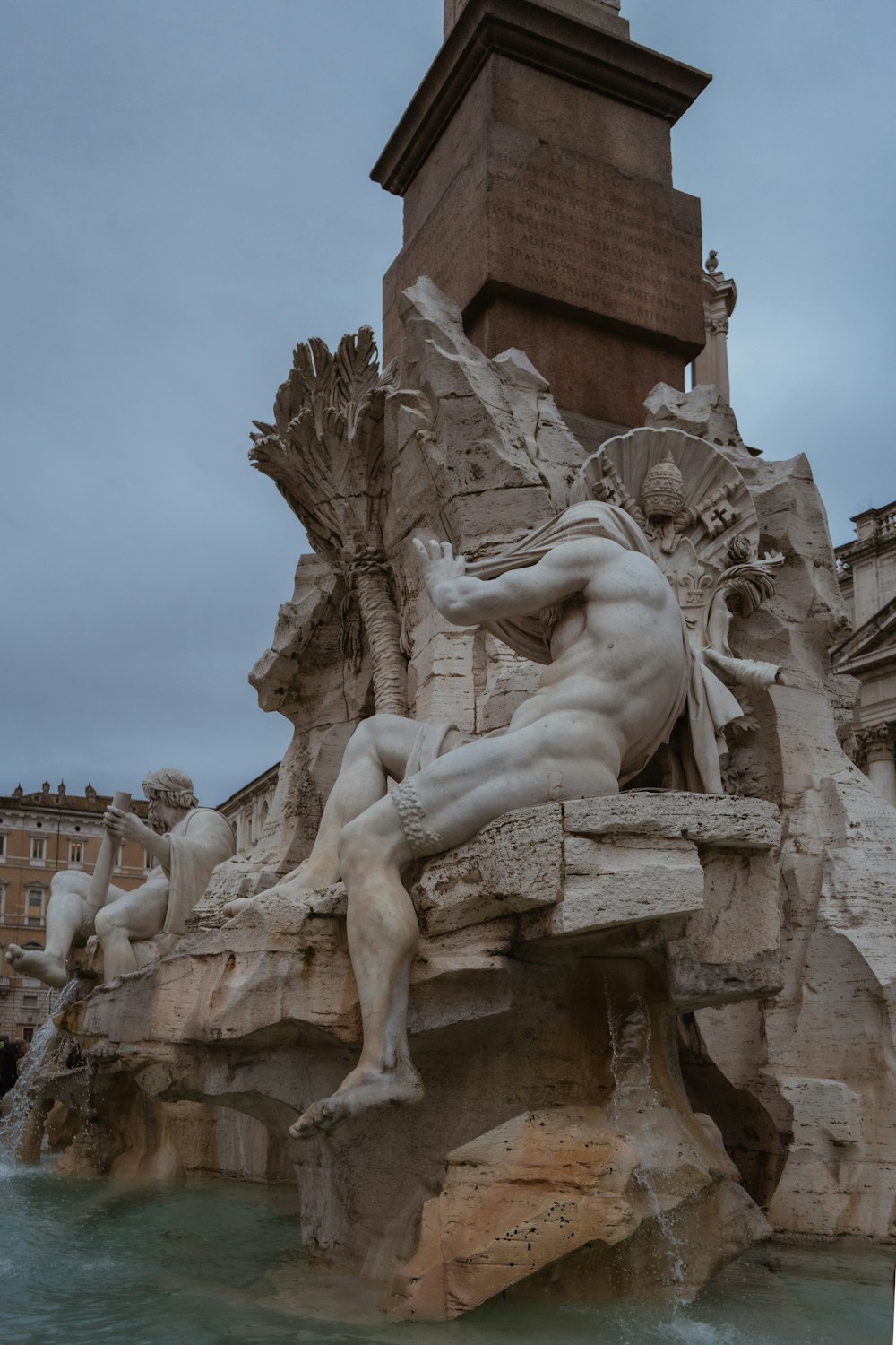 a statue of a man sitting on a bench next to a fountain