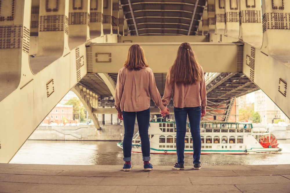 Zwei Frauen halten Händchen, während sie unter einer Brücke stehen